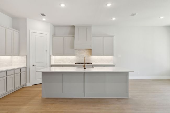 Kitchen featuring a center island with sink, decorative backsplash, light countertops, light wood-style floors, and recessed lighting | Image 14