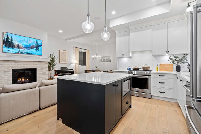 Kitchen featuring light wood finished floors, light countertops, white cabinetry, stainless steel gas stove, and a center island | Image 12