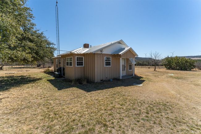 View of property exterior featuring metal roof, a lawn, board and batten siding, and a chimney | Image 17