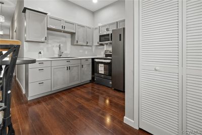 Kitchen featuring gray cabinetry, stainless steel appliances, dark hardwood / wood-style floors, and sink | Image 2