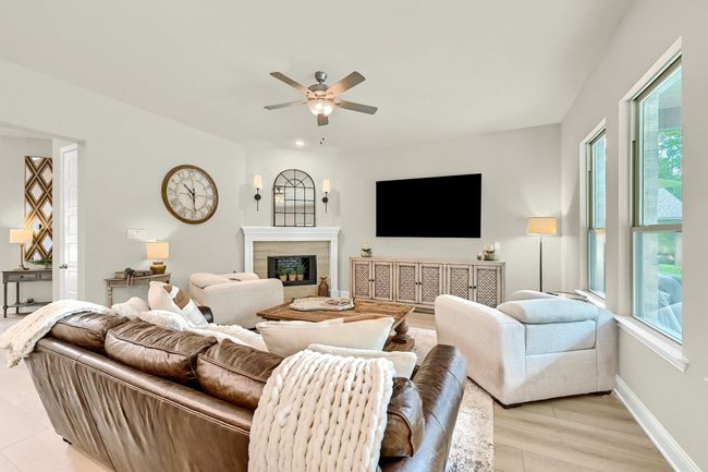 Living area with light wood finished floors, a high end fireplace, ceiling fan, and plenty of natural light | Image 14