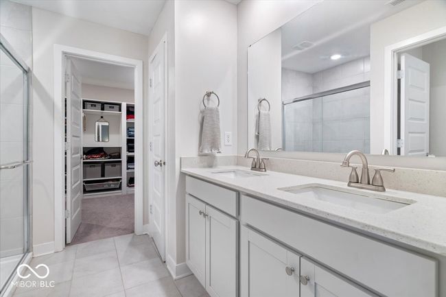 full bathroom with a walk in closet, a stall shower, double vanity, and tile patterned flooring | Image 24