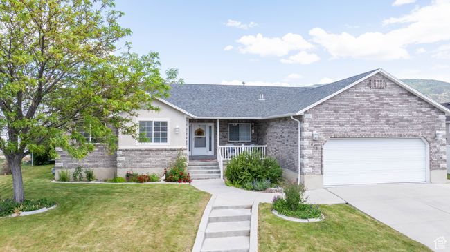 Single story home with a garage, a porch, concrete driveway, a front lawn, and brick siding | Image 4