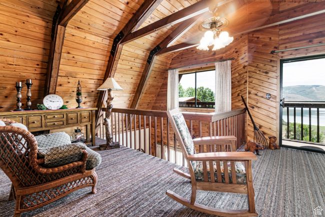 Living area with carpet floors, wooden ceiling, wooden walls, and a chandelier | Image 11