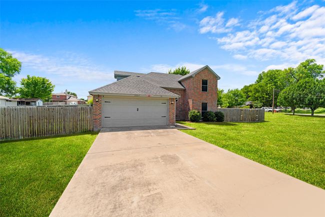 Traditional-style home featuring brick siding, concrete driveway, a garage, and a shingled roof | Image 4
