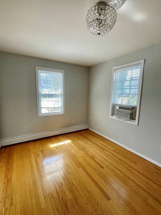 Unfurnished room with cooling unit, wood finished floors, a baseboard heating unit, and a wealth of natural light | Image 14