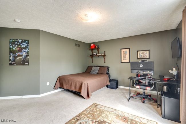 Carpeted bedroom featuring a textured ceiling and a desk | Image 27