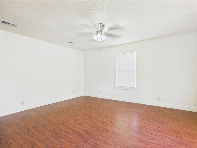 Unfurnished room featuring a ceiling fan, wood finished floors, and a textured ceiling | Image 7