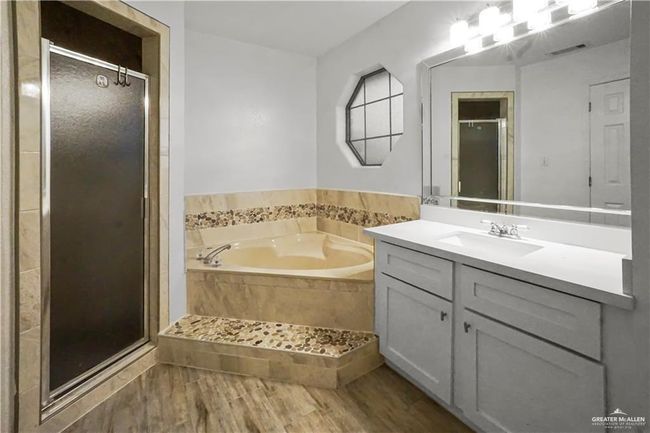 Bathroom featuring vanity, a stall shower, a garden tub, and wood finished floors | Image 5