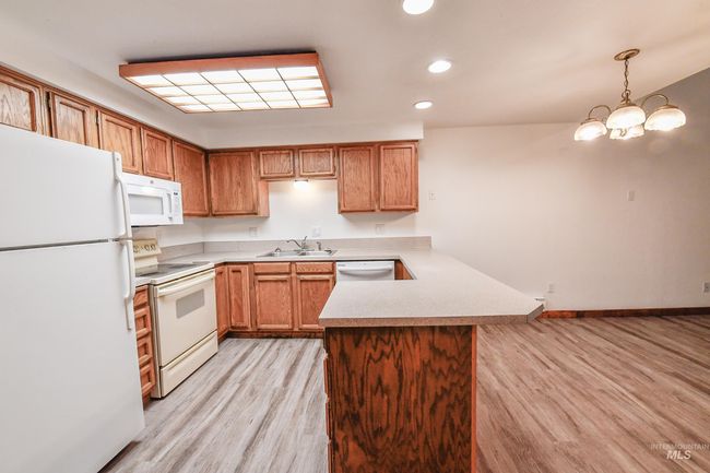 Kitchen with white appliances, a peninsula, light wood-style floors, light countertops, and recessed lighting | Image 10
