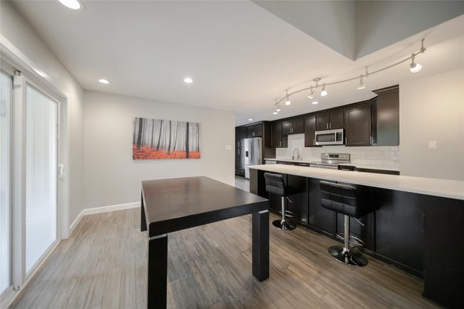 Kitchen featuring appliances with stainless steel finishes, light countertops, light wood-style floors, backsplash, and recessed lighting | Image 7