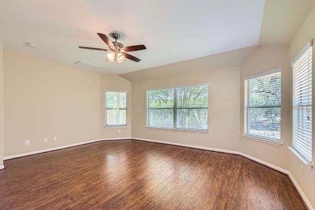 Primary bedroom with a ceiling fan, dark wood-type flooring, healthy amount of natural light, vaulted ceiling, bay windows | Image 17