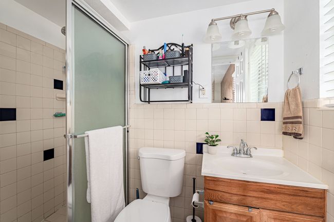 Bathroom with tile walls, toilet, a stall shower, and vanity | Image 30