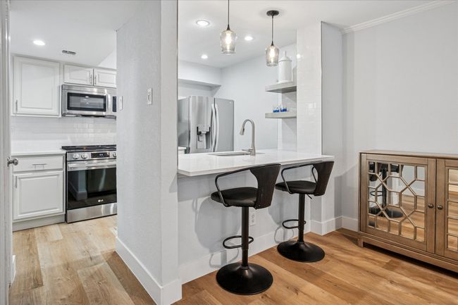 Beautifully updated kitchen with counter height serving bar, stainless appliances and subway tiled backsplash. | Image 5