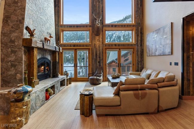 Living area with a high ceiling, wood finished floors, and a stone fireplace | Image 28