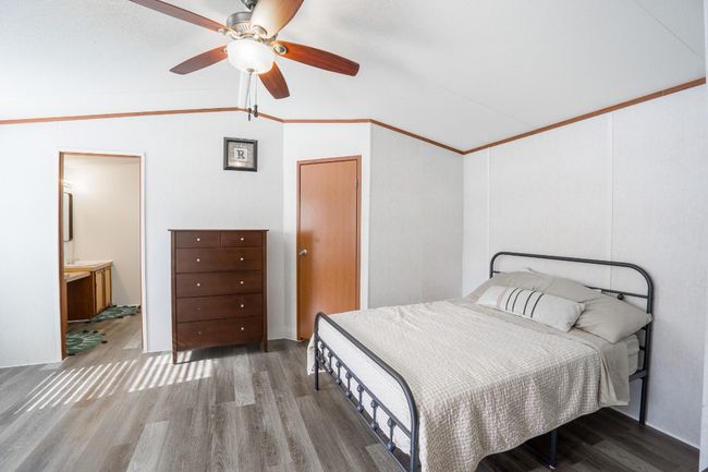 Bedroom featuring vaulted ceiling, wood finished floors, a ceiling fan, and connected bathroom | Image 16
