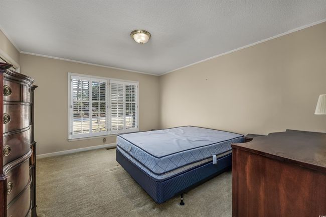Bedroom featuring a textured ceiling, light colored carpet, and ornamental molding | Image 24