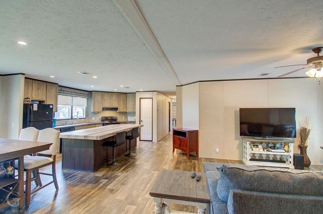 Living room featuring a textured ceiling, wood finished floors, ceiling fan, and recessed lighting | Image 4