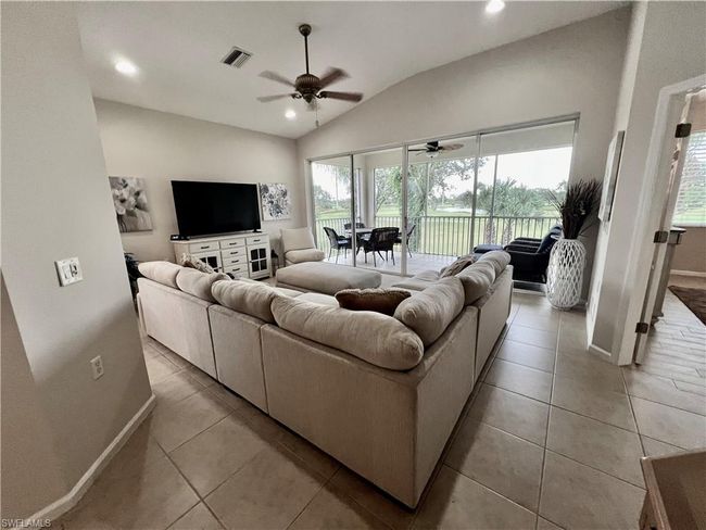 Living room with ceiling fan, light, tile floors, and high ceilings before furniture removed | Image 13