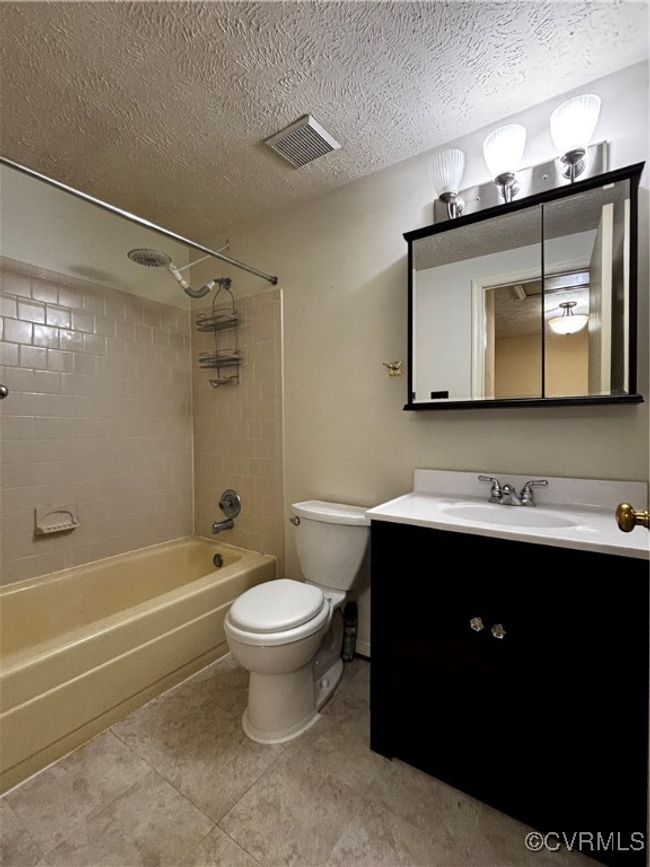 Full bath featuring shower / bath combination, vanity, a textured ceiling, and tile patterned flooring | Image 11