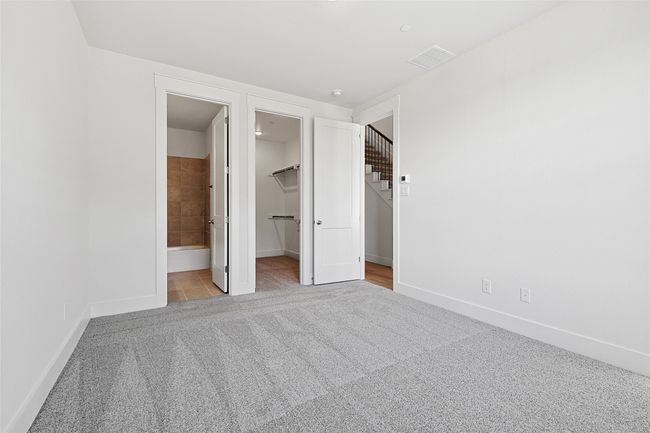 Unfurnished bedroom featuring a closet, light colored carpet, connected bathroom, and a walk in closet | Image 38