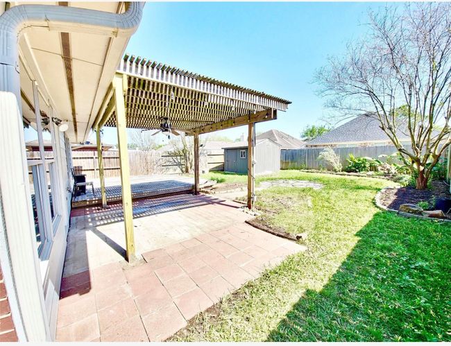 Fenced backyard with ceiling fan, a patio, and a storage unit | Image 25