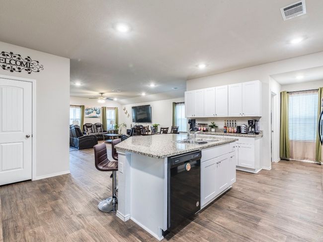 Kitchen with open floor plan, a center island with sink, a sink, visible vents, and dishwasher | Image 7