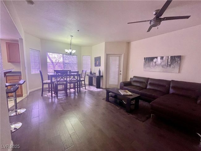 Living room with dark wood-style flooring, baseboards, a textured ceiling, and ceiling fan with notable chandelier | Image 16