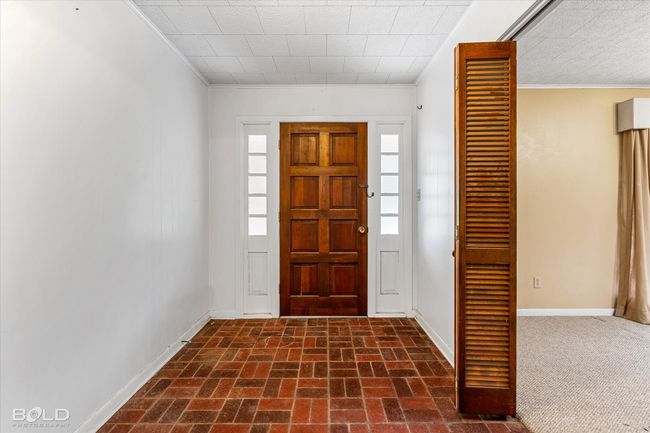 Foyer entrance with crown molding, baseboards, and brick patterned flooring | Image 4