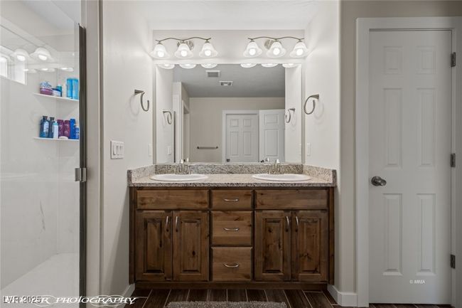 Bathroom with double vanity, a stall shower, wood finished floors, and baseboards | Image 41