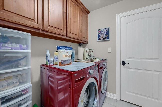 Washroom featuring baseboards, separate washer and dryer, cabinet space, and light tile patterned floors | Image 16