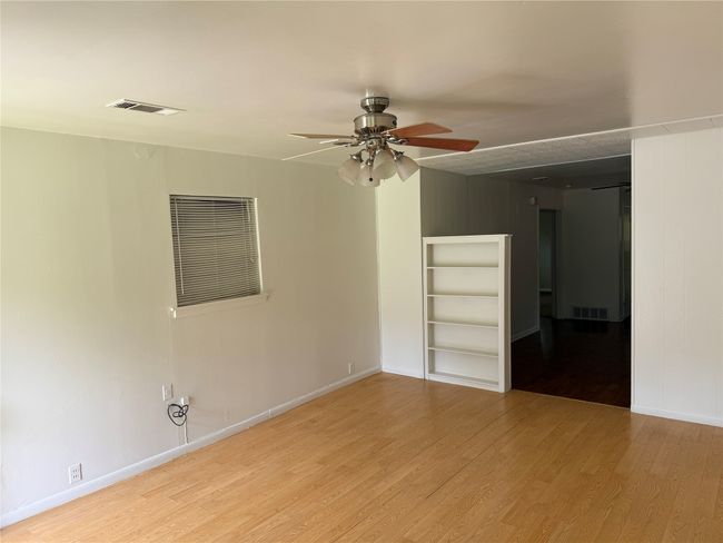 Spare room featuring ceiling fan, wood finished floors, and built in shelves | Image 7