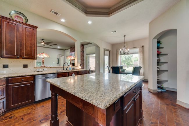 Kitchen featuring dishwasher, dark wood-style floors, light stone counters, backsplash, and a ceiling fan | Image 18