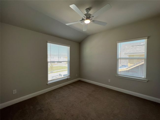 Spare room featuring dark colored carpet, baseboards, ceiling fan, and vaulted ceiling | Image 18