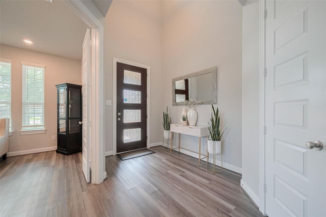 This inviting home entryway features a modern door with frosted glass panels, light color flooring, and neutral walls. | Image 7