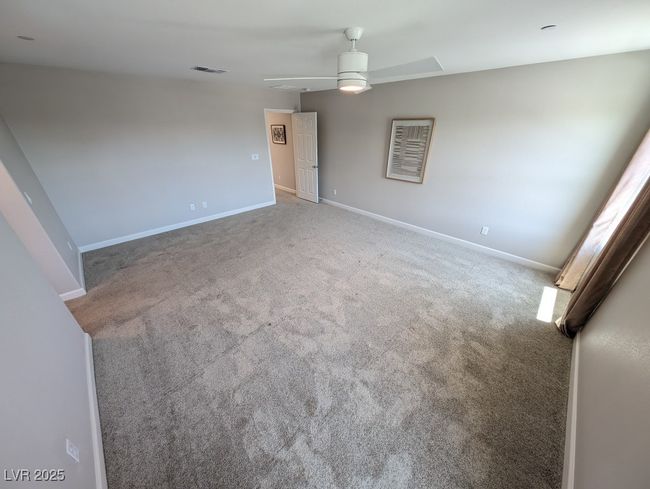 Empty room with ceiling fan, carpet, and attic access | Image 21