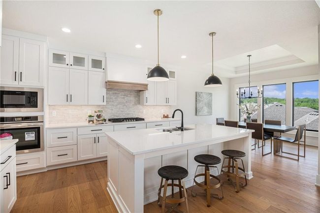 Kitchen featuring appliances with stainless steel finishes, light wood finished floors, backsplash, a breakfast bar, and recessed lighting | Image 8