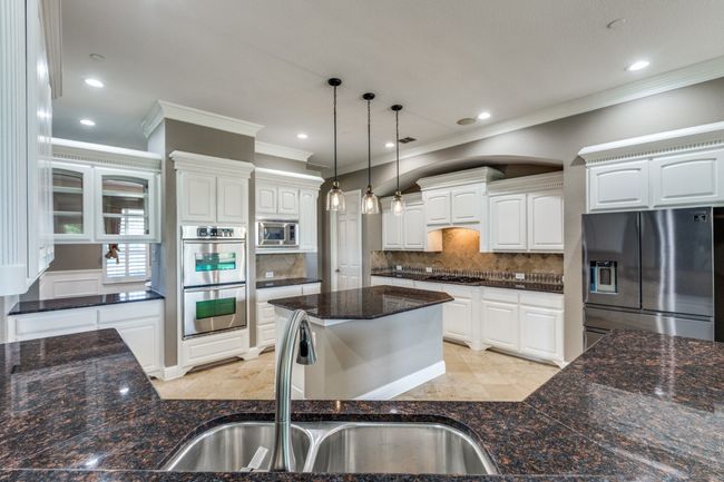 Kitchen with stainless steel appliances, a sink, ornamental molding, backsplash, and decorative light fixtures | Image 14