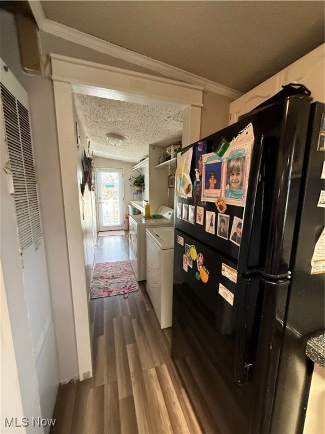 Hall featuring washing machine and dryer, crown molding, wood finished floors, and a textured ceiling | Image 13