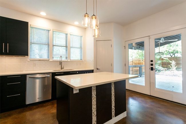 Kitchen with dishwasher, dark cabinetry, finished concrete floors, light countertops, and decorative backsplash | Image 9