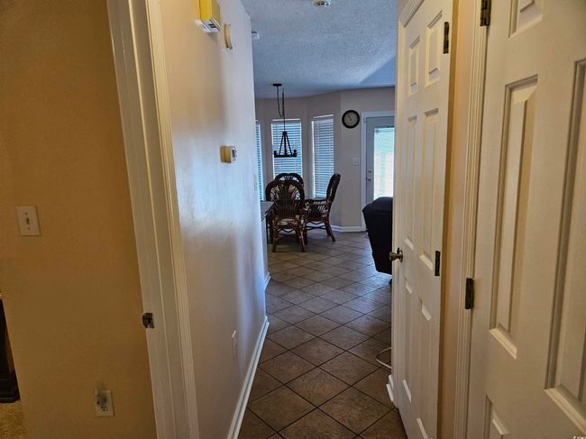 Hall with a textured ceiling and dark tile patterned floors | Image 13