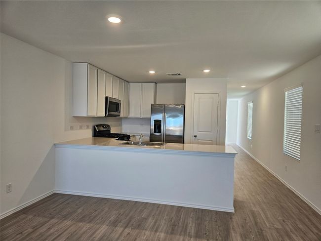 Kitchen with visible vents, dark wood finished floors, appliances with stainless steel finishes, a peninsula, and a sink | Image 6