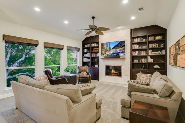 Family room with ceiling fan, built in shelves, lofted ceiling, and light colored carpet | Image 8