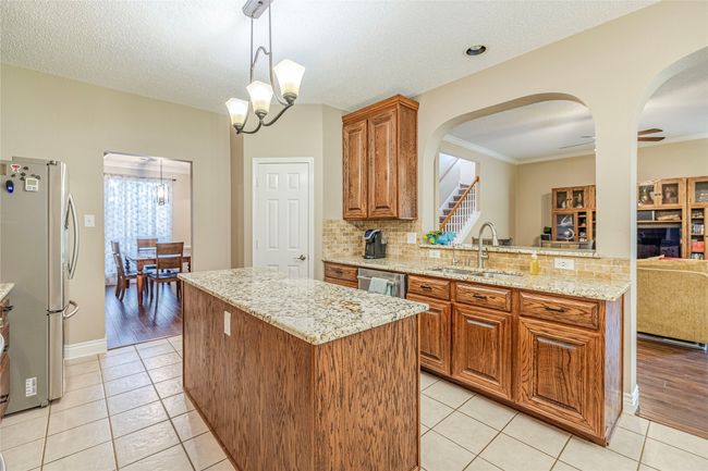 Kitchen with appliances with stainless steel finishes, a sink, a kitchen island, a chandelier, and arched walkways | Image 17