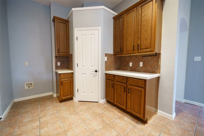 Kitchen with brown cabinets, light countertops, and decorative backsplash | Image 14