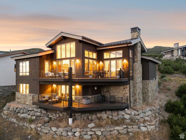 Back of house with stone siding, a standing seam roof, a chimney, and a balcony | Image 7