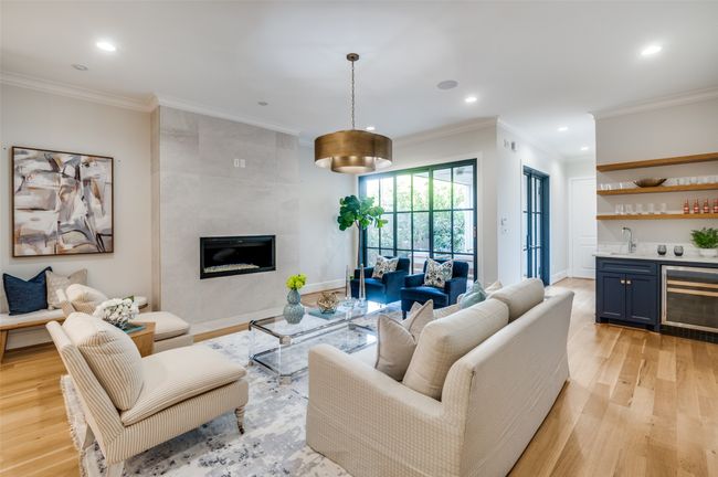 Living room with light wood-style flooring, wet bar, wine cooler, and crown molding | Image 4