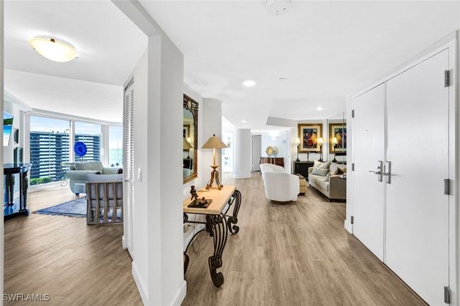 Hall with a wall of windows, wood finished floors, and baseboards | Image 4