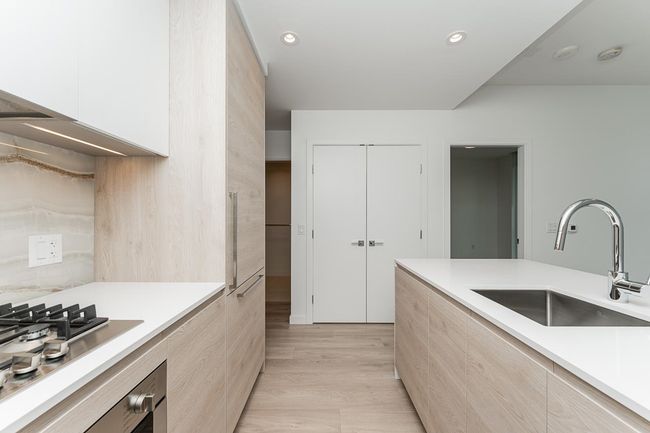 Kitchen with stainless steel gas cooktop, light countertops, a sink, and modern cabinets | Image 11