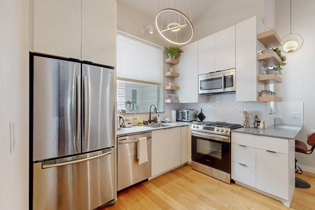 Kitchen with open shelves, appliances with stainless steel finishes, a sink, and light wood-style floors | Image 15